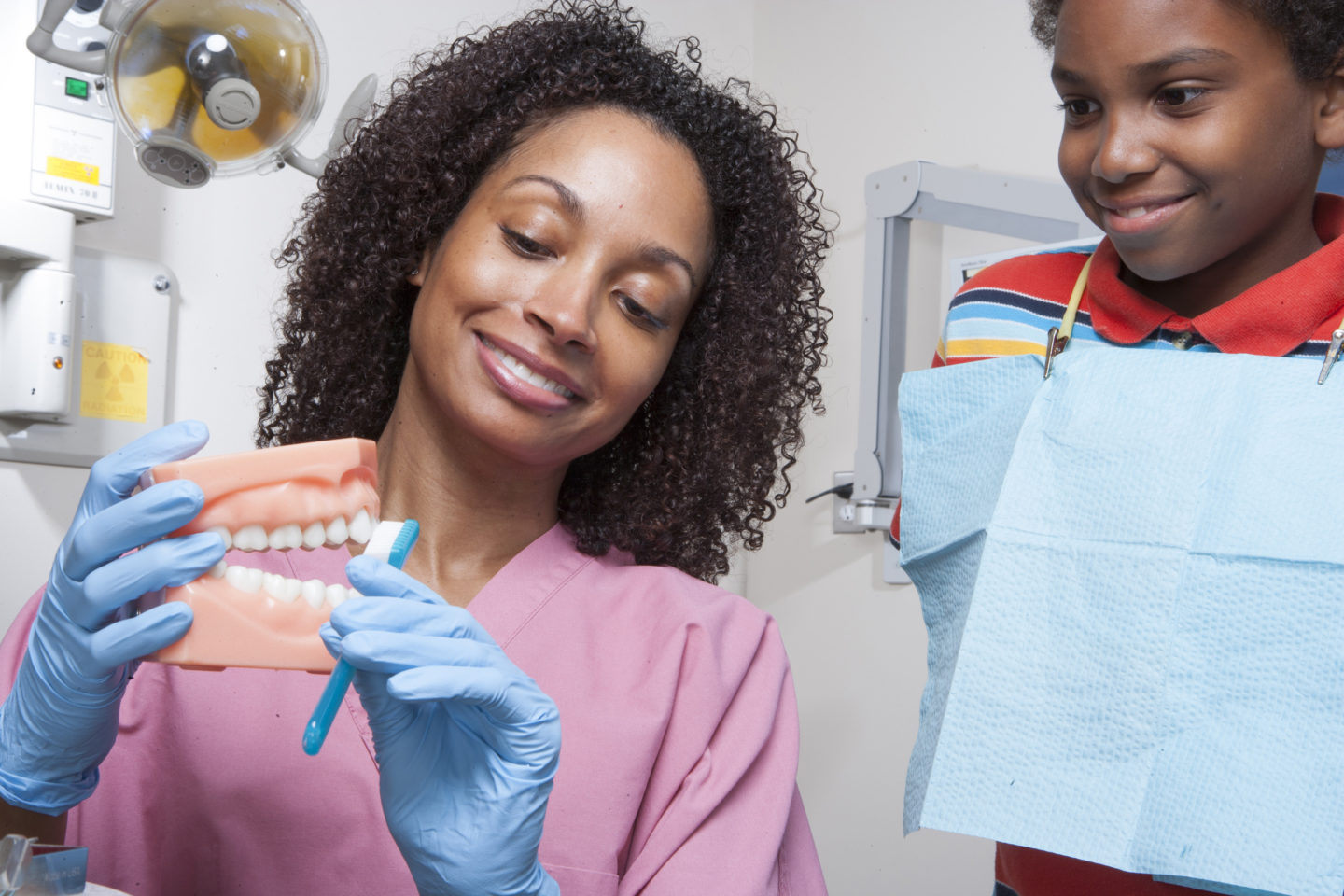 Dentist teaching patient to brush teeth