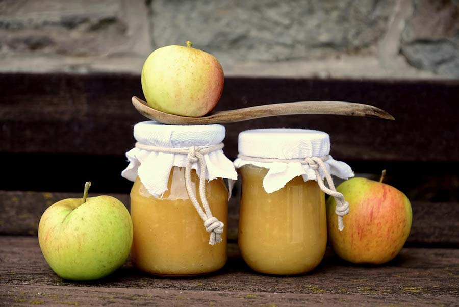 Apples near two jars of applesauce, which is a recommended food to eat with canker sores