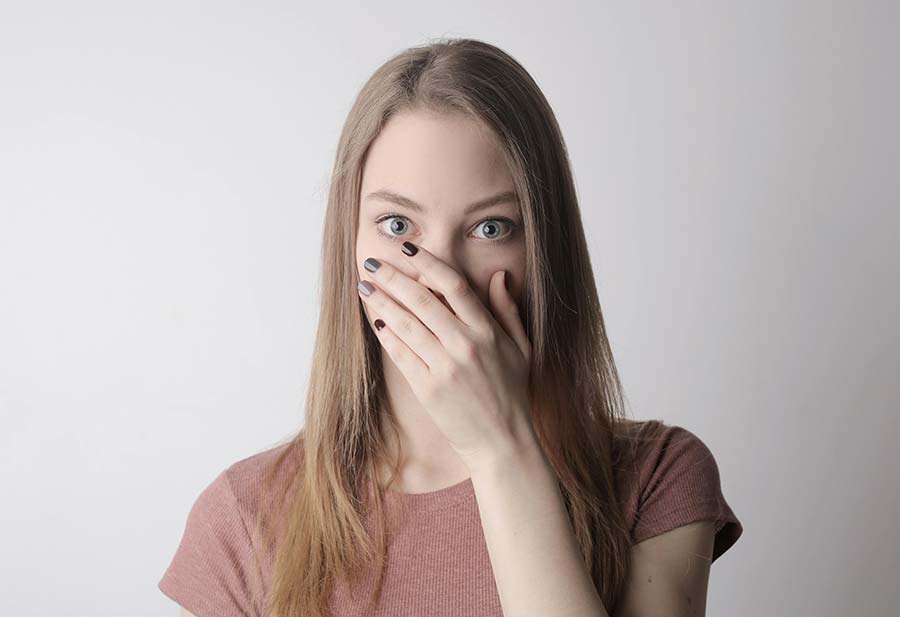 A person placing their hand over their mouth after experiencing the symptoms of black tongue